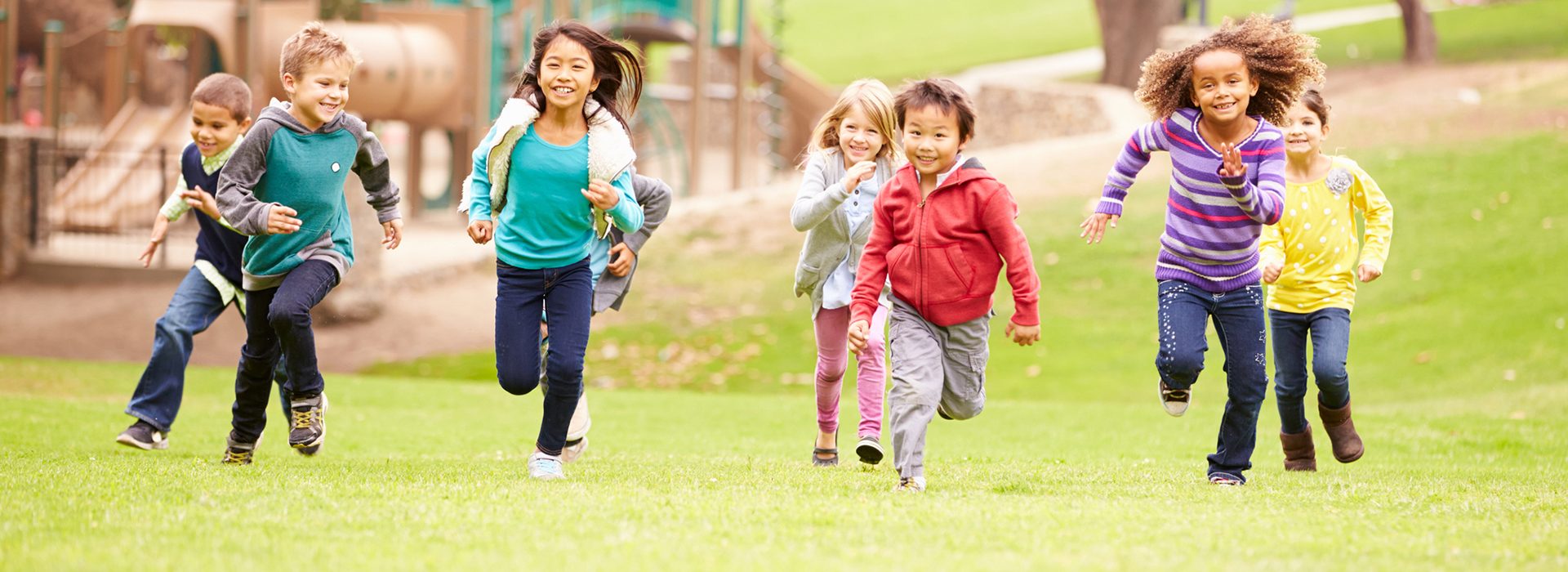 Children running across a park lawn